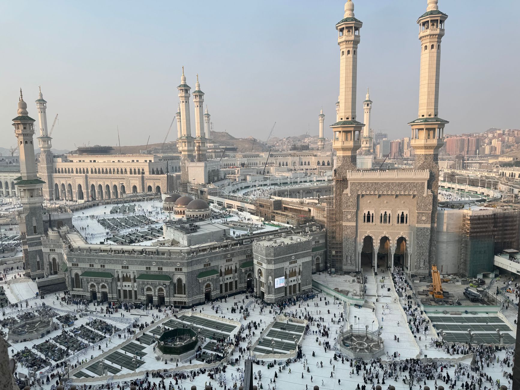 Aerial view of Masjid al-Haram and Kaaba in Mecca, with pilgrims gathered for prayer.